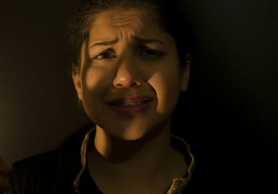 Close-up portrait of smiling woman against black background