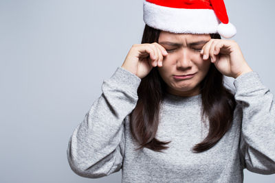 Portrait of sad young woman against gray background