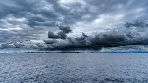 Scenic view of sea against storm clouds