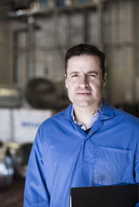 Front view portrait of confident male electrician standing in industry