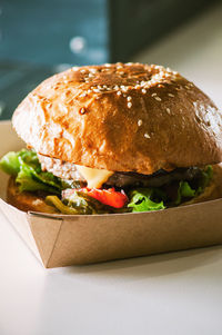 Close-up of freshly prepared cheeseburger in a box on table.