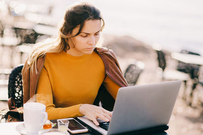 Mid adult woman using laptop on table