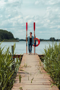 Full length of young woman standing by sea against sky