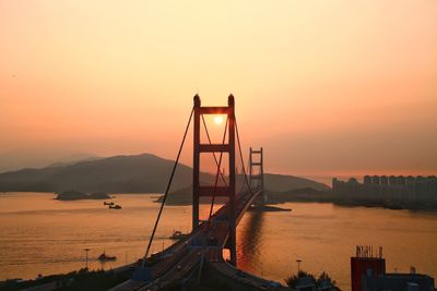 View of suspension bridge in sea during sunset