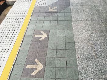 High angle view of arrow sign on pavement