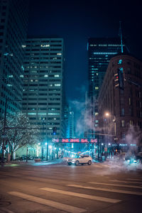 Illuminated city street and buildings at night