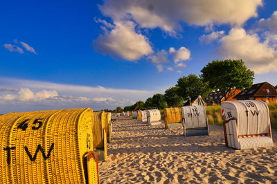 Hooded chairs on beach against blue sky