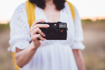 Midsection of woman holding camera outdoors