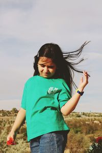 Young woman standing against sky