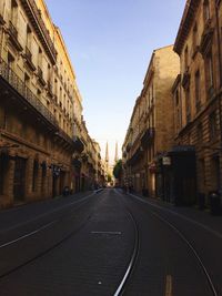 Empty road amidst buildings against clear sky