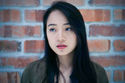 Portrait of a beautiful young woman against brick wall