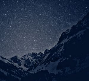 Scenic view of snowcapped mountain against star field at night