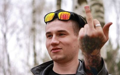 Young man with sunglasses showing obscene gesture