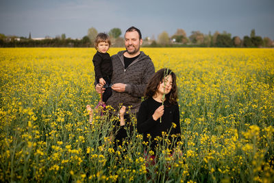 Smiling family of three kids and a father standing amidst yellow flowers
