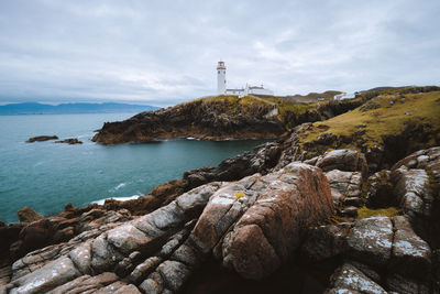 Lighthouse by sea against sky