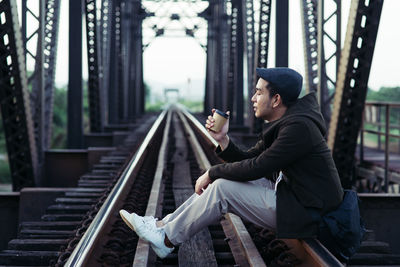 Side view of man sitting on mobile phone