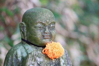 Close-up of woolen pom-pom on buddha statue