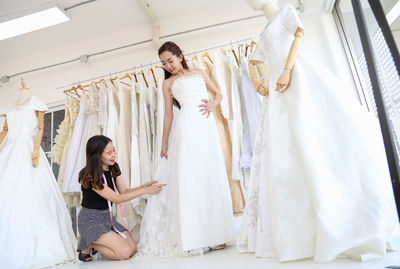 Tailor looking at woman wearing wedding dress in bridal shop