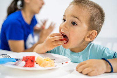 Close-up of boy eating fruits on table at home