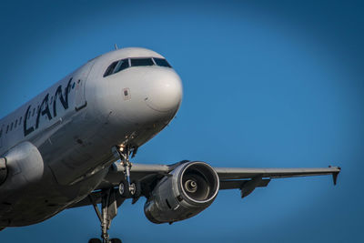 Low angle view of airplane against clear blue sky