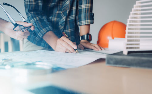 Midsection of engineer making blueprint at desk in office