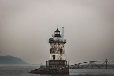 Lighthouse by sea against sky