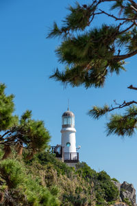 Lighthouse by trees against sky