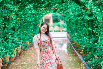 Portrait of smiling young woman standing against plants