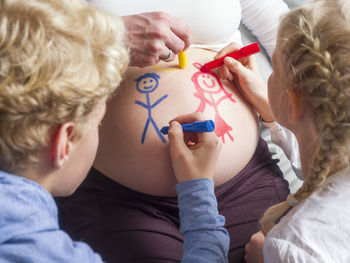 Children painting on pregnant mother's belly