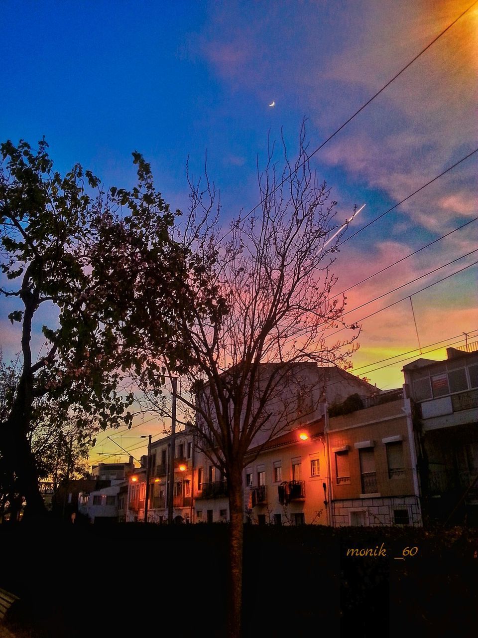 building exterior, architecture, built structure, sunset, sky, house, tree, bare tree, residential building, power line, silhouette, residential structure, low angle view, cloud - sky, dusk, building, orange color, electricity pylon, city, outdoors