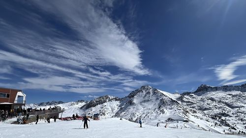 People skiing on snow covered mountains against sky