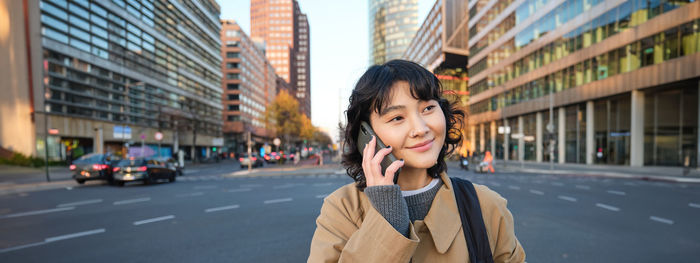 Portrait of young woman standing in city