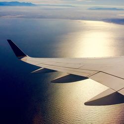 Cropped image of airplane wing over clouds