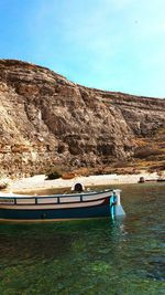 Boat moored on shore against clear sky