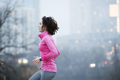 Side view of woman exercising in city during sunrise