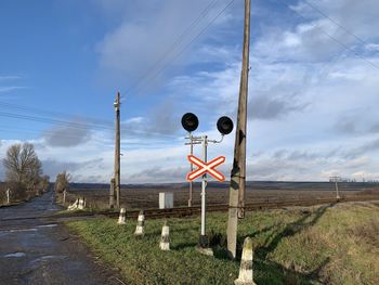 Road sign on field against sky