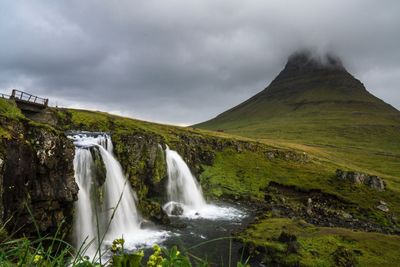 View of waterfall against cloudy sky