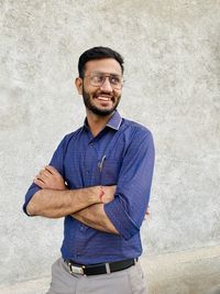 Portrait of young man standing against wall