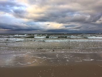 Scenic view of beach against cloudy sky