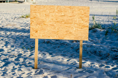 Billboard on the beach with place for your text. wooden plaque without inscriptions.