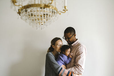 Full length of mother and daughter standing against wall