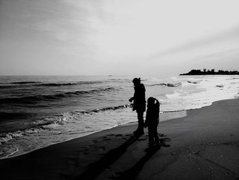 Men standing on beach against sea