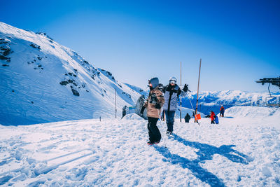 People skiing on snow covered mountain against sky