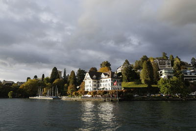 Scenic view of river by buildings against sky