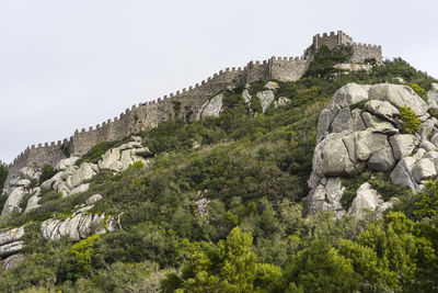 Low angle view of rock formations and castle against sky