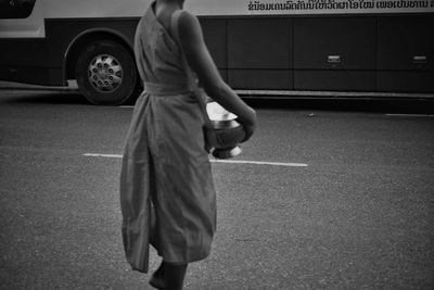 Midsection of woman holding container while walking on street