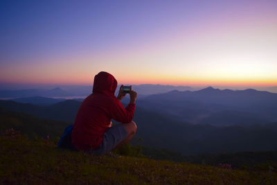 Man photographing on mountain at sunset