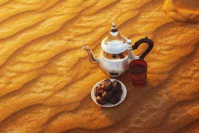 Arabian teapot, cup and dates in the desert at a beautiful sunset symbolizing ramadan