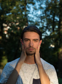 Portrait of young man standing against trees