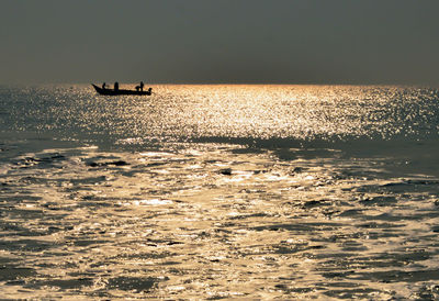 Silhouette boat sailing in sea against sky during sunset